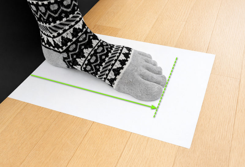 Foot on a sheet of paper against a wall, with the length and the longest toe marked